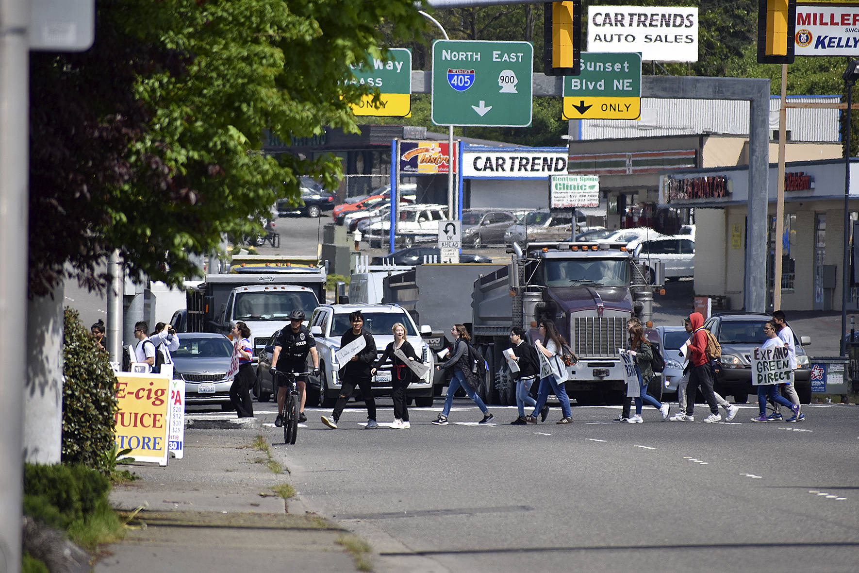 Photo by Haley Ausbun. Students cross the street at a busy intersection at Northeast Third Street and Sunset Boulevard with the help of Renton police officers.