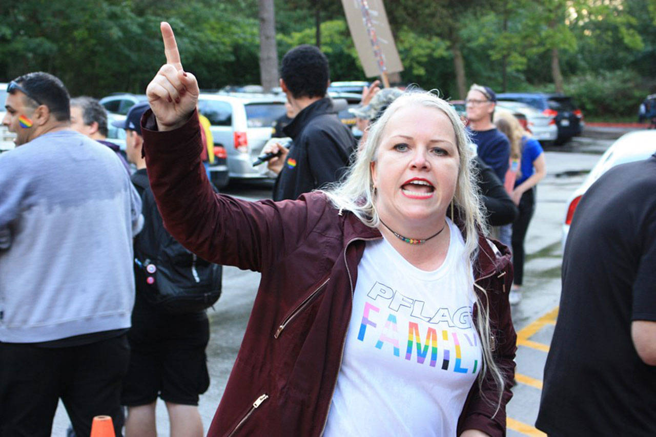 Jen Carter, vice chair of the King County Democrats, leads supports in chants to drown out a street preacher protesting the reading event. Aaron Kunkler/staff photo