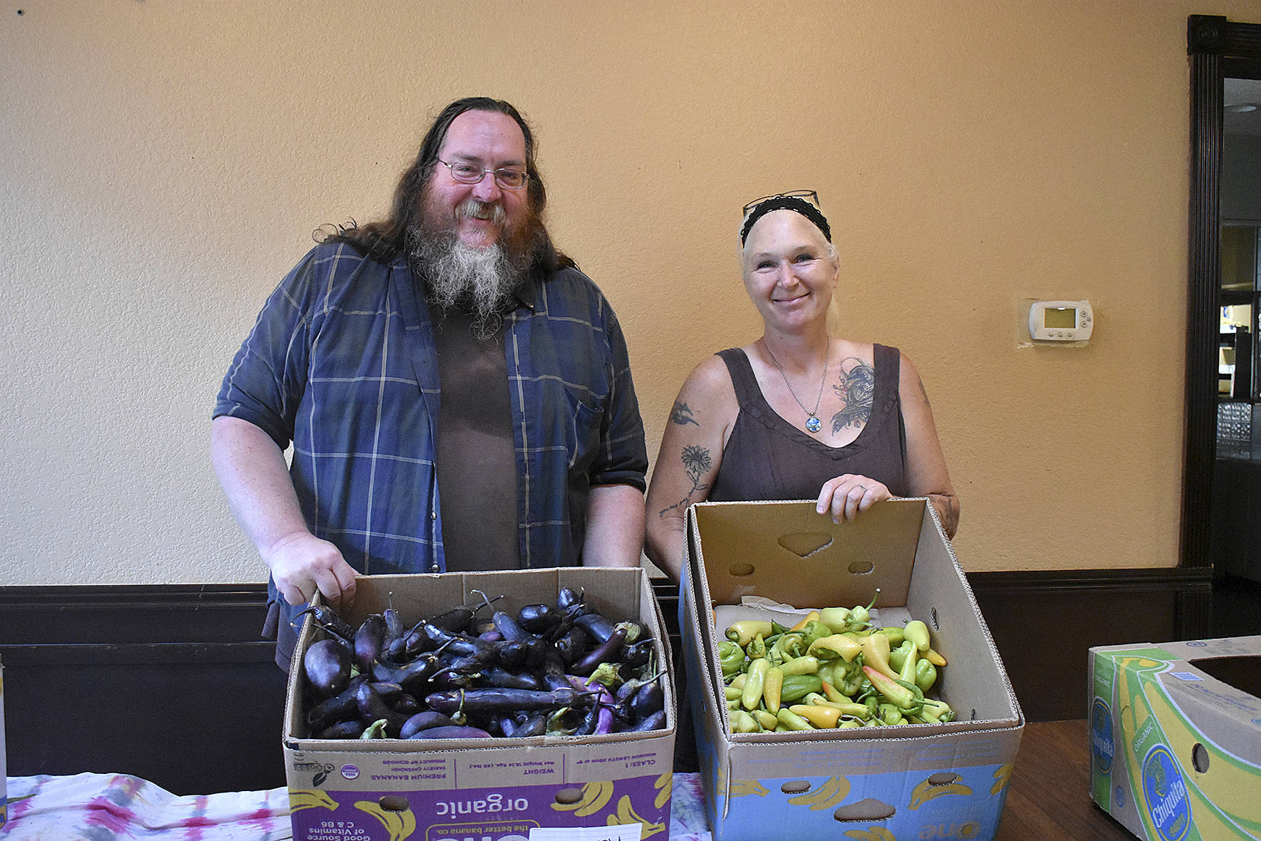 Scott Kreidermacher, left, and Lara Randolph, right, hold up the food that remains from a busy day at the Free Grocery Store, a new project from nonprofit Sustainable Renton, on Monday, Aug. 19. Photo by Haley Ausbun.