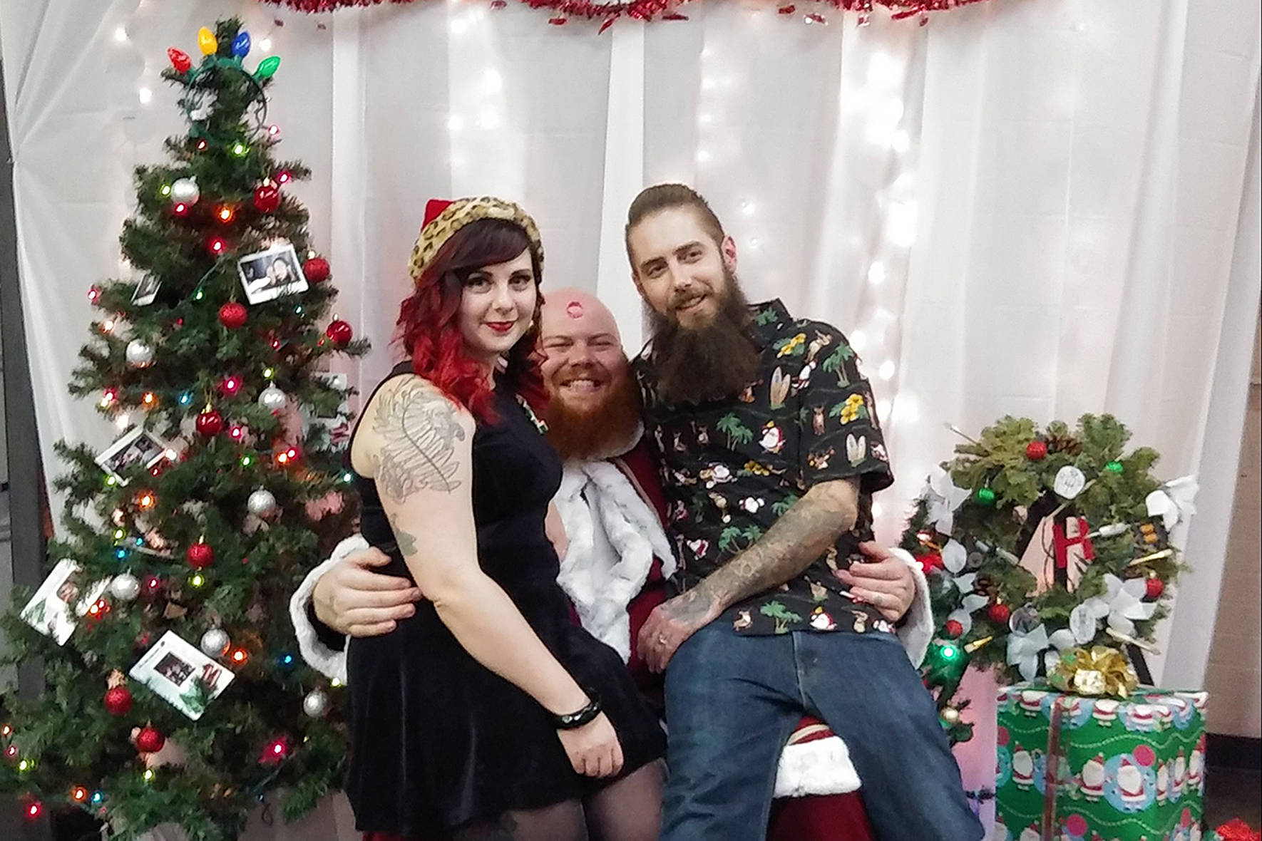 Photo courtesy of Handsome Devil Ink. Owners Maggie and Ryan Hammond with Bad Santa (center) at their annual Bad Santa Food Drive.