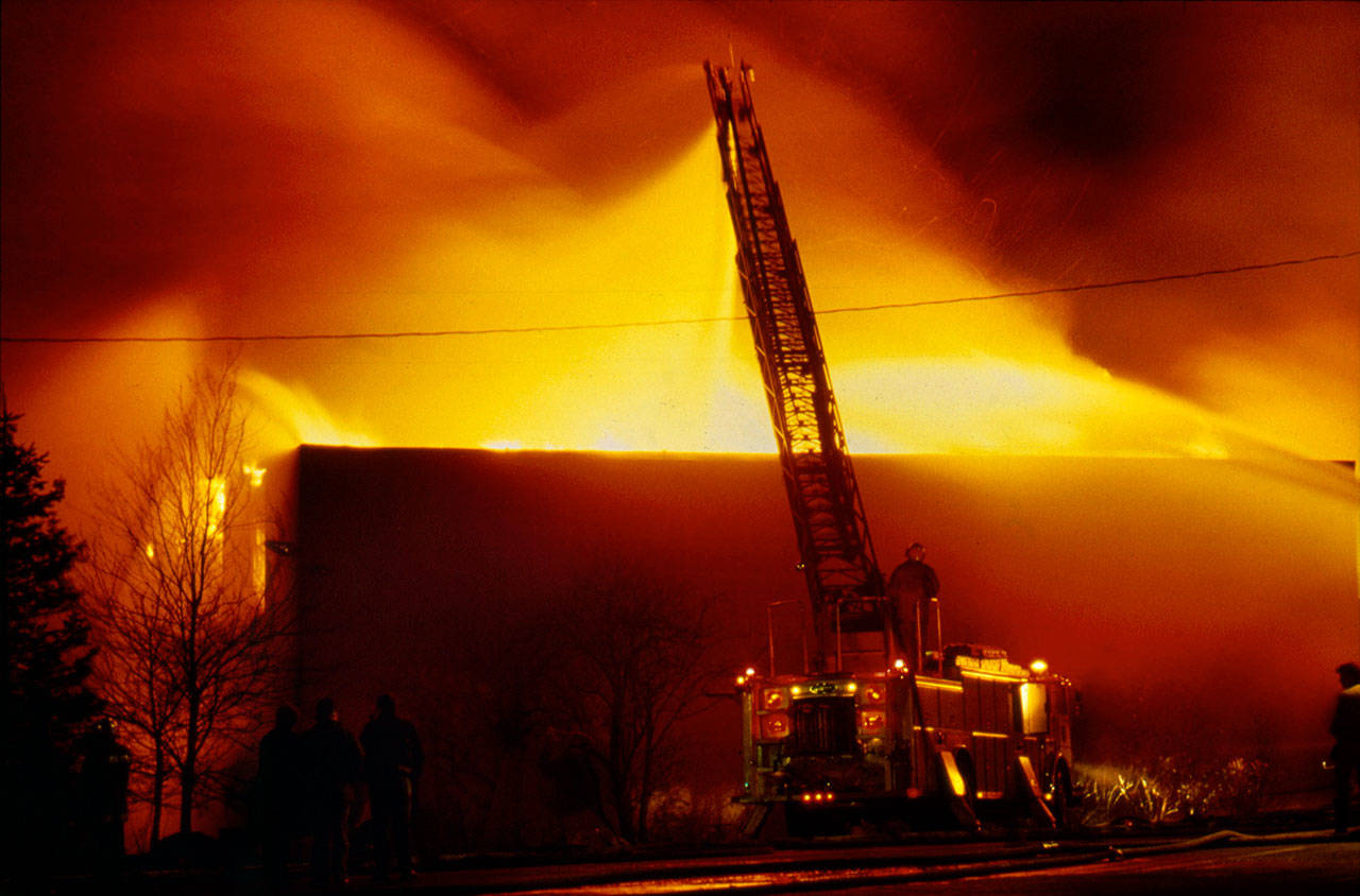 A ladder truck shoots water over the south wall of the Everett Community College library complex on Feb. 16, 1987. The arson destroyed the facility and killed Everett firefighter Gary Parks. (Michael O’Leary / Herald file)