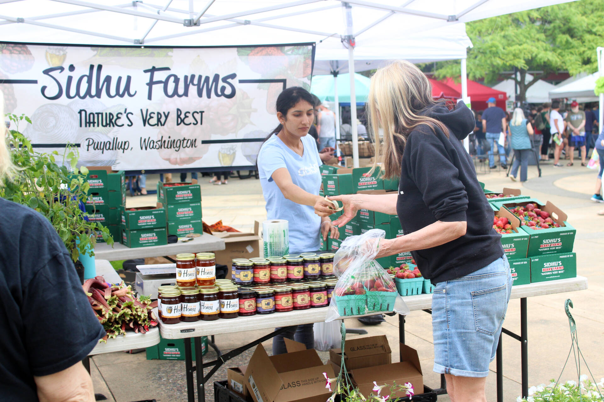 A customer buys strawberries from Sidhu Farms at the Renton Farmers Market. Photo: Bailey Jo Josie/Sound Publishing