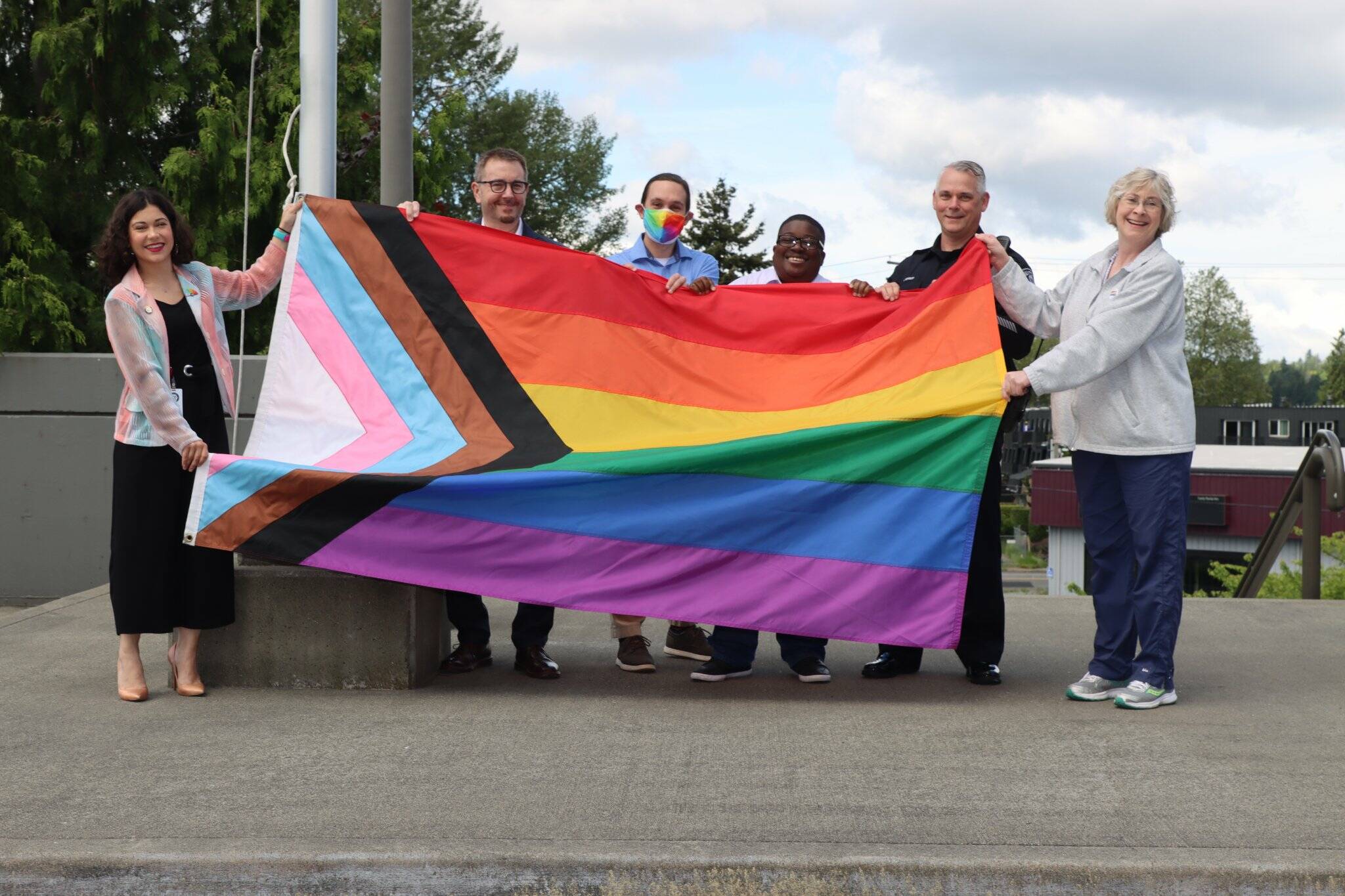 (From left to right) Renton City Councilmember Carmen Rivera, Mayor Armondo Pavone, Councilmember Ryan McIrvin, Councilmember Ed Prince, Police Chief Jon Schuldt and Councilmember Valerie O’Halloran hold the Progress Pride flag outside of City Hall. Photo courtesy of the City of Renton.