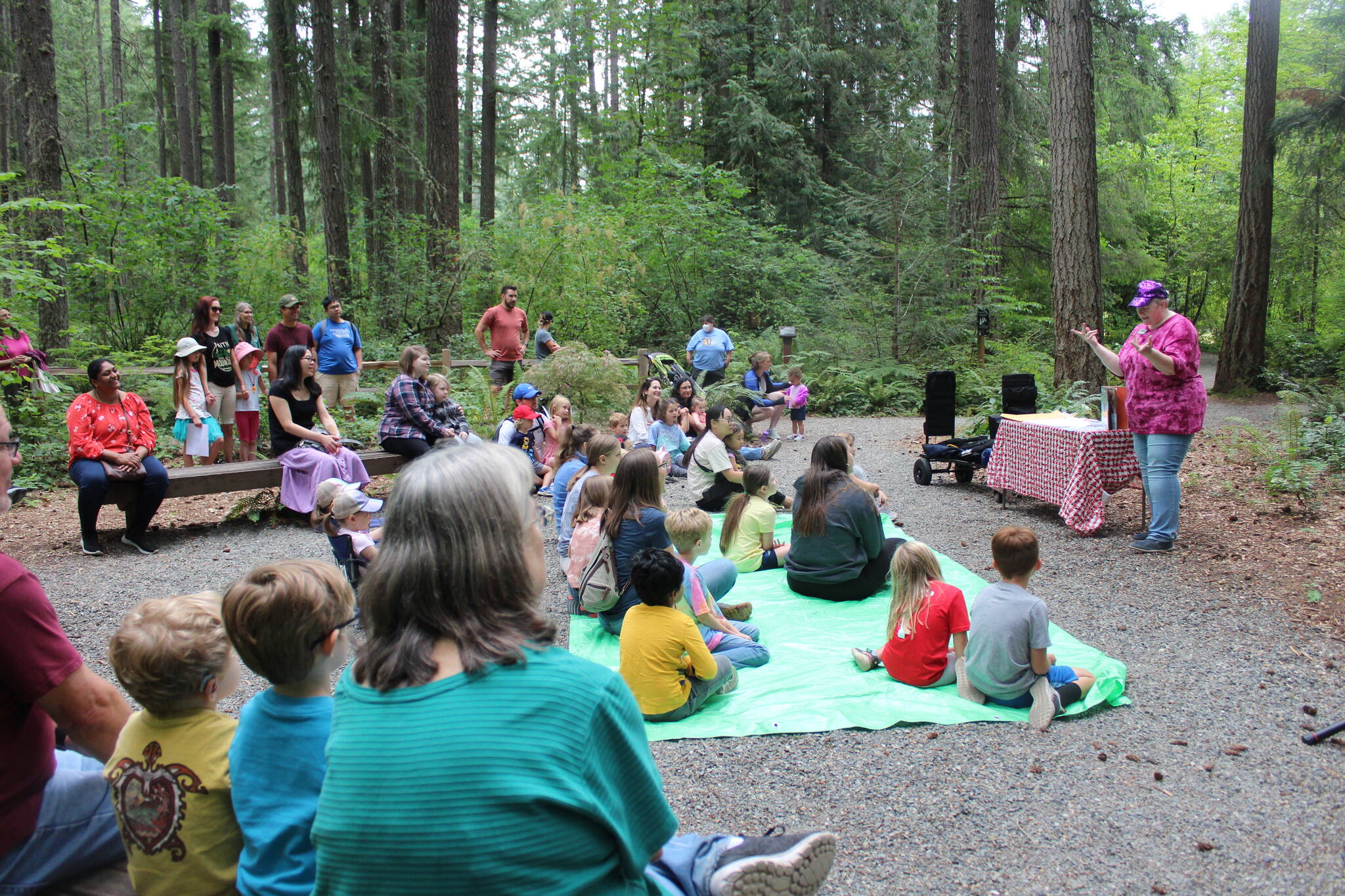 Children, parents, guardians and families gather in the Lake Wilderness Arboretum as Maple Valley librarian Sharon Chastain talks about the trees. Photo by Bailey Jo Josie/Sound Publishing.