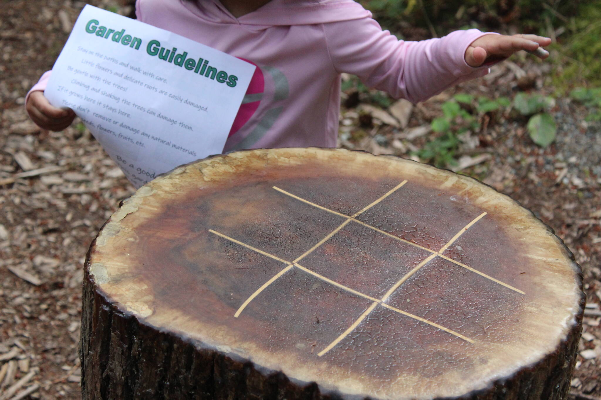 A little girl touches the tic-tac-toe game in the Lake Wilderness Arboretum during the Tree Tour. Photo by Bailey Jo Josie/Sound Publishing.