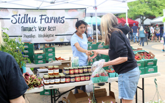 A customer buys strawberries from Sidhu Farms at the Renton Farmers Market. Bailey Jo Josie/Sound Publishing photo