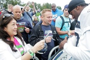 A big part of the Bing Seahawks Training Camp is getting autographs from favorite players. Hundreds of fans attended the first of 15 open practices today at the Virginia Mason Athletic Center. Misa Seely of Bothell and Mark Nielsen of Puyallup get their footballs autographed by Jordan Babineaux.