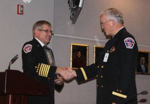 Fire Chief Mark Peterson presents a certificate of appreciation to Chaplain Allan Folmar on his retirement.