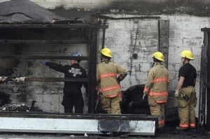 A King County Sheriff's Office fire investigator and Skyway firefighters work to find a cause of a commercial fire in Skyway Tuesday evening.