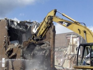An excavator with a claw digs away Thursday at the a building on the First Savings Bank Northwest campus on Wells Avenue in downtown Renton. The bank plans to build a four-story loan center in its place.
