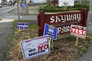 Annexation signs vie for attention on Renton Avenue in Skyway. The large one in the background tells about an community meeting Tuesday night.