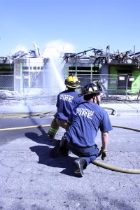 Two Renton firefighters put out flames about 10 hours after a four-alarm fire burned the Harington Square apartments.