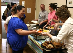 Kimm Baxter accepts a chicken dinner from volunteers at the Renton Community Supper. The supper opened Monday night at the Renton Salvation Army Church.