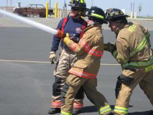 Assistant Editor Brian Beckley wrestles with the high pressure hose as shadow Firefighter Jesse Mitchell of the Valley Regional Fire Authority braces him during FireOps 101.