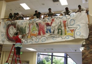 Renton High School senior class president Vanessa Tran helps straighten the senior class centennial banner from a ladder in the Renton High School student commons Tuesday. It was spirit week for Renton High