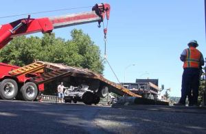 Workers lift a truck that broke an axle when it hit a curb on the turn from Mill Avenue to Bronson Way Thursday afternoon
