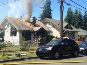 Firefighters cut a hole in the roof of a home in North Renton on July 24 to vent smoke and heat.