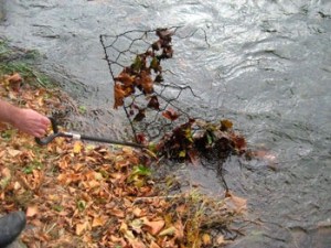 A public works employee fishes a damaged gabion out of the river. The metal cages will be replaced this month.