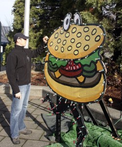 Ryan Fleming of Fleming's Holiday Lighting checks a bulb on the Holiday Hamburger display Tuesday at Gene Coulon Memorial Beach Park during a walkthrough of the Ivar's Clam Lights with City of Renton employees.