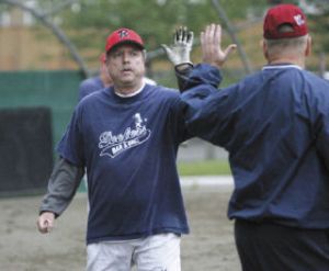 Mike Spellman high fives base coach and teammate Marvin Yost as he comes in after scoring a run.