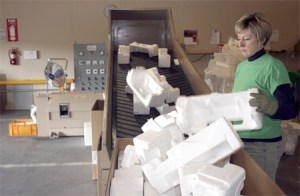 Katherine English  tosses in styrofoam to be processed into 40-pound ingots. The ingots are formed from the long stream of heated material that’s coming out of the machine at the far left.