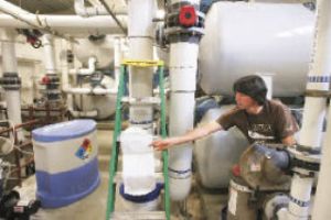 Renton aquatics coordinator Dave Perkins changes pool filters Wednesday as he and staff prepare the Henry Moses Aquatic Center for a June opening.