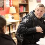 With the crust from lunch still in front of them, Officer Thaddeus Kerkhoff talks with a Renton High School student during this week&rsquo;s &ldquo;Pizza with the Popo.&rdquo; (Leah Abraham | Renton Reporter)