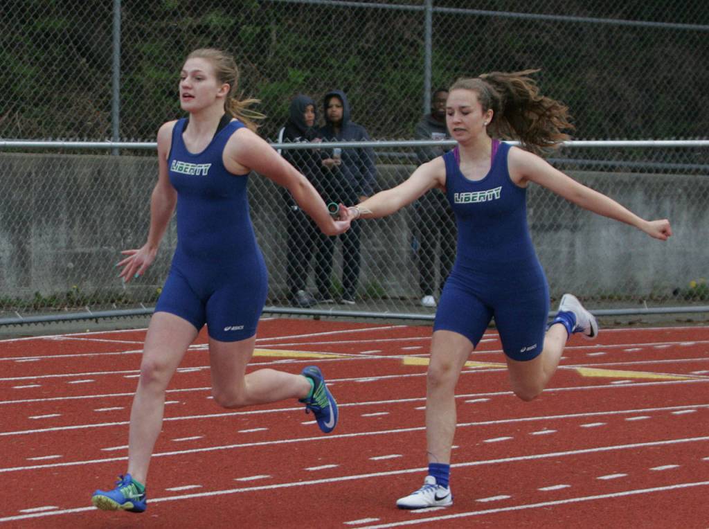 Natalie Surber (left) grabs the baton from McKaye Noel during the girl&rsquo;s 4x100 meter relay.