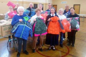 St. Anthony parishioners hold up coats they are donating to the Coats for Kids effort. (Courtesy photo)