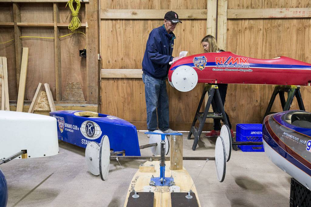 As her grandfather, Rich McCalib, wipes down the car, Alexie Crabtree removes a decal from her soap box car. (Andy Bronson / The Herald)