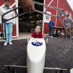Peyton Calkins listens as adults talk about the bend in a rod that keeps the wheels straight under pressure from the drivers weight in a soap box derby car. (Andy Bronson / The Herald)