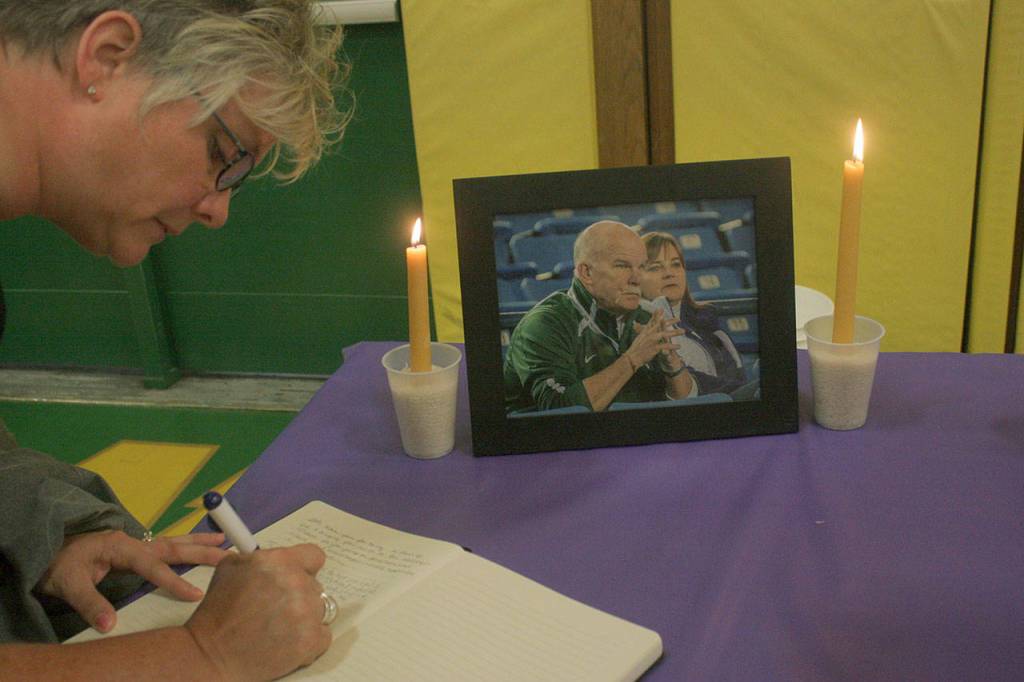 Carrie Lantz signs a memorial book before the start of a candlelight vigil for Kentridges longtime athletic director Eric Anderson, who died Saturday at age 57. MARK KLAAS, Kent Reporter