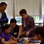 Photo by Haley Ausbun. Japan congress members observe a sixth grader at Renton Prep as she works on her Minecraft museum project.