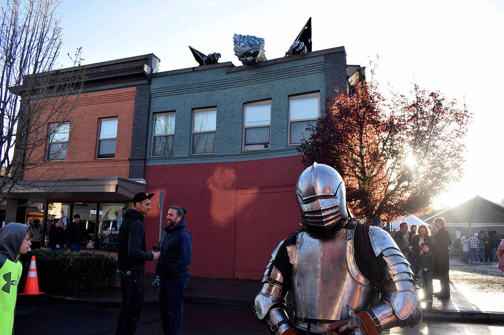 Mike Bergstrom in an impressive suit of armor stands valiantly amidst the newest addition to the downtown  a dragon. Photo by Haley Ausbun.