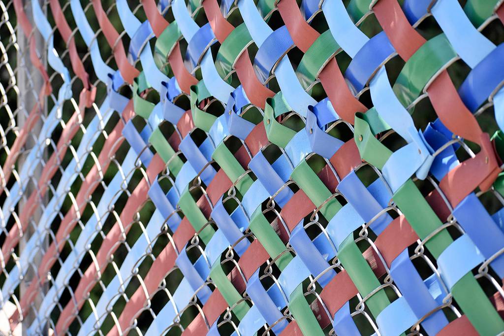 Photo by Haley Ausbun. The fence now has woven with colorful privacy tape, plaques containing six languages and over 100 symbols that were created by students and residents in the Sunset neighborhood.