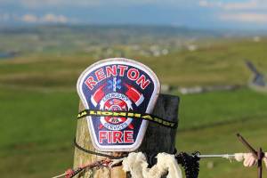 Courtesy of Renton Regional Fire Authority. A fence alongside the coastline and emerald green fields of Cliffs of Moher in Ireland sits a Renton RFA patch, honoring a fallen firefighter whos legacy inspired a local nonprofit.