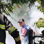 Photo by David Nelson. A neighbor uses a garden hose as Bellevue firefighters arrive.
