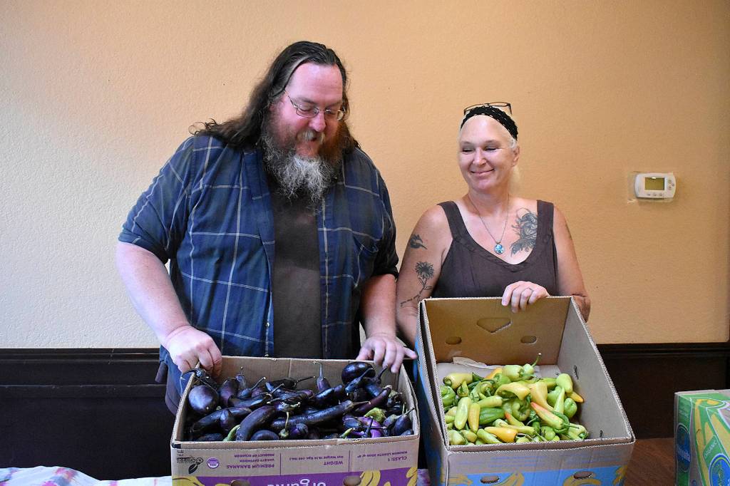 Scott Kreidermacher, left, and Lara Randolph, right, hold up the food that remains from a busy day at the Free Grocery Store, a new project from nonprofit Sustainable Renton, on Monday, Aug. 19. Photo by Haley Ausbun.