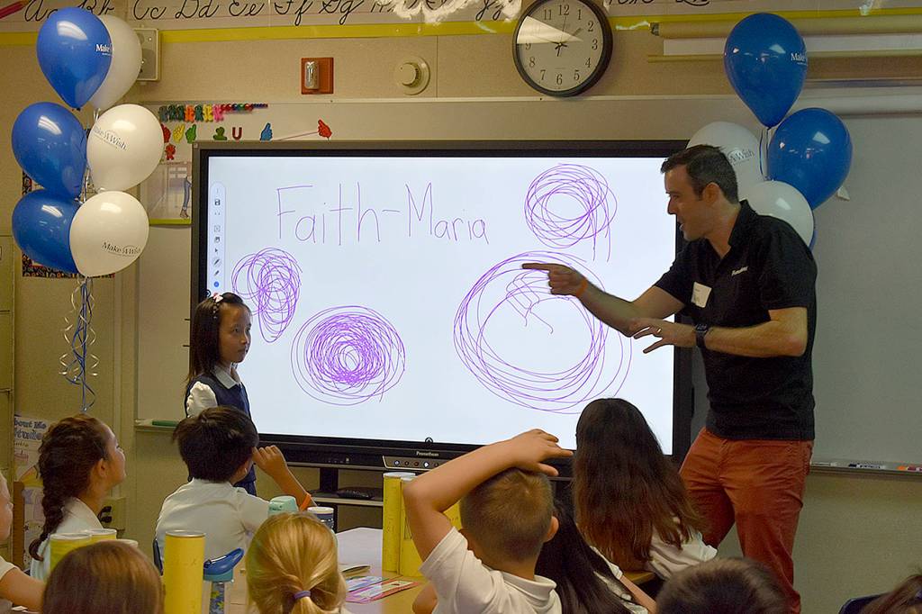 Photo by Haley Ausbun. Faith-Maria, a third grader at St. Anthony Elementary School in Renton and Leukemia survivor, asked Make-a-Wish to share her wish with her school, which resulted in two new smart boards. Students got to try them out at the unveiling, Sept. 12.