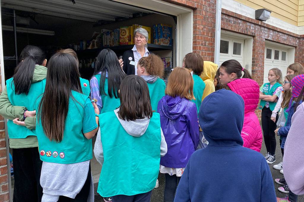 Photo by Haley Ausbun. Girl Scouts from troops 46754, 41126 and 41170 put together 400 sandwhich lunches on Saturday, Nov. 9 as part of Vision House kids serve event. The lunches then went to people experiencing homelessness in Seattle via Union Gospel Mission Search and Rescue. Here Vision Houses Venetia Vango offers girl scouts a tour of their residents store, where they give families living in Vision House apartments a free shopping experience twice a month.