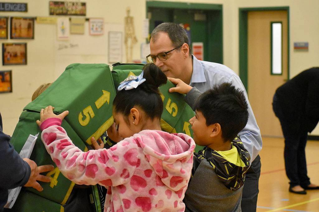 Photo by Haley Ausbun. Pictured: Students at Highlands Elementary School work on an impressive feat of civil engineering, with the help of a representative of the Pacific Science Center (right).