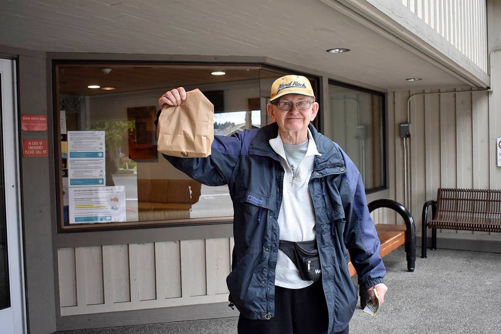 Photo by Haley Ausbun. Pictured: Bob, a Renton resident, picks up his drive thru lunch from the Renton Senior Activity Center, March 10. With the center closed through March 31 due to the coronavirus outbreak, staff are finding a clever way to get the critical lunch program out to seniors. For many seniors, staff say, its the only meal they have for the day. The drop-in lunch program now has sack lunches instead of a hot lunch. They will be available for drive through pick-up only, Monday through Friday from 11:30 a.m. to 12:30 p.m.