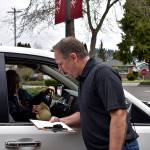 Photo by Haley Ausbun. With the Renton Senior Activity Center closed through March 31 due to the coronavirus outbreak, staff are finding a clever way to get the critical lunch program out to seniors. For many seniors, staff say, its the only meal they have for the day. The drop-in lunch program now has sack lunches instead of a hot lunch. They will be available for drive through pick-up only, Monday through Friday from 11:30 a.m. to 12:30 p.m. Staff are trying to get the word out after the number of lunch participants dropped from 60 to 70 folks to only four or five after the senior center closed Friday, March 6. Pictured: Renton Senior Activity Center staff walk out to cars or pedestrian seniors, have them sign off and hand them the bagged lunch, March 10.