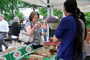 Photo by Haley Ausbun                                A woman checks out jars of honey and jam at the Renton Farmers Market in 2018. This year social distancing guidelines are changing the look of the market.