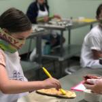 A young chef carefully spreads sauce onto pizza dough during a cooking class at Young Chefs Academy of Covington. Courtesy photo/YCA Covington