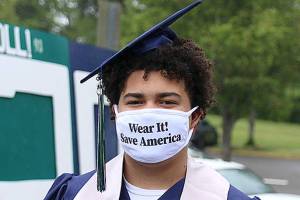 In this file photo, Tayshon Cottrell dons his graduation cap and gown, along with a face mask reading: Wear it! Save America at Todd Beamer High Schools virtual graduation walk recording on May 20, 2020, in Federal Way. Olivia Sullivan/Sound Publishing