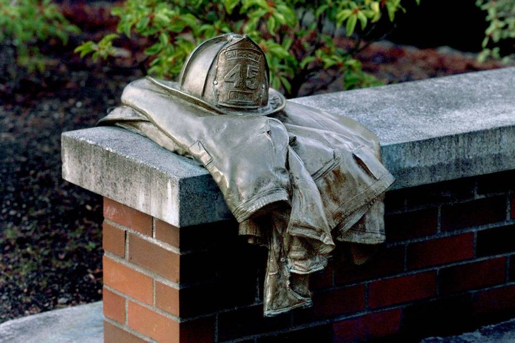 A bronze firefighters helmet and turnout jacket is mounted on a bench at a Gary Parks memorial outside the Everett Community College library. (Dan Bates / Herald file)