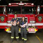 South King Fire and Rescue Lt. Ann Hoag, left, holds her son Flynn and firefighter Amanda Weed holds her daughter, Parker, in the engine bay of Station 63 on March 9, recreating a photo the two took months before while pregnant. Olivia Sullivan / The Mirror