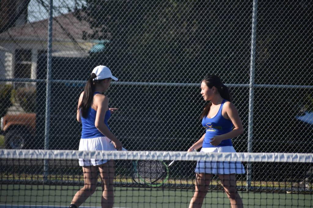 Hazens Ava Chinn and Jasmin Wong tap racquets at Renton High during their victory. Ben Ray / The Reporter