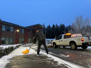 Renton School District grounds staff Andrew Seccomb drives the snowplow and Risdon Middle School custodian Floyd Adkins clears the sidewalk before students and staff arrive at work. Photo provided by Renton School District.